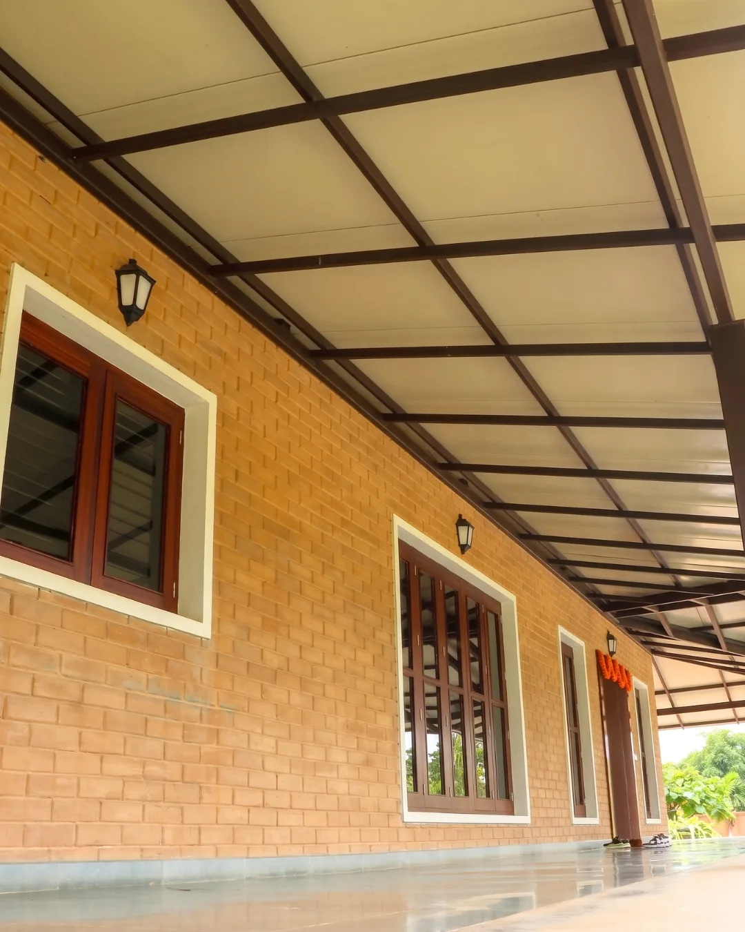 A verandah running the length of an earth-block wall under a steel-framed roof