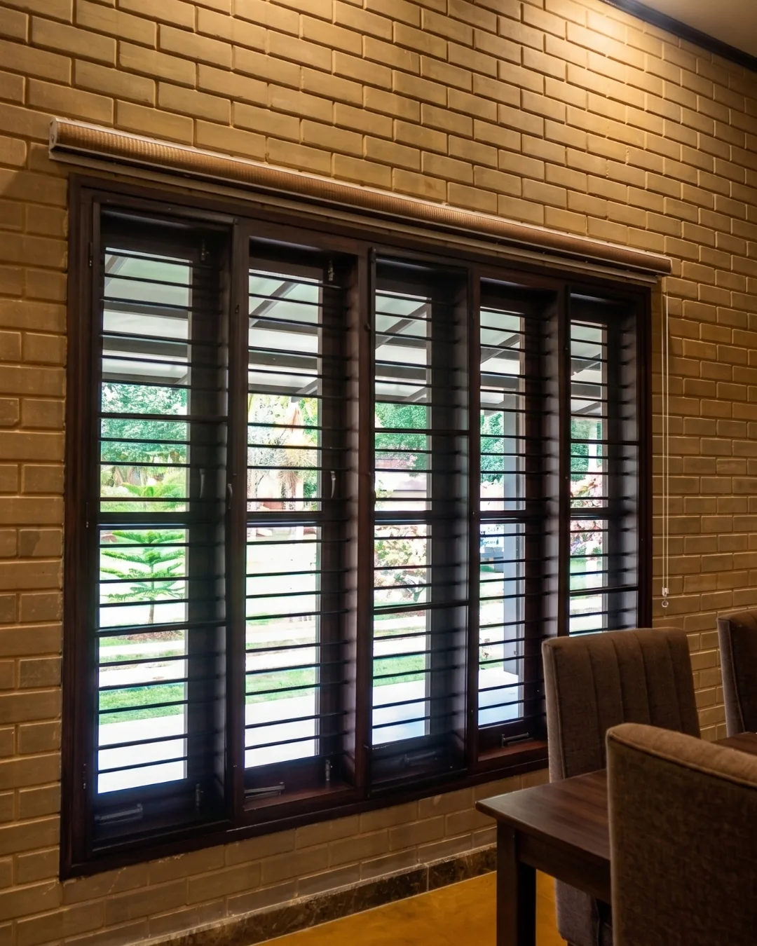 A louvred timber window in an earth-block wall, from the dining room