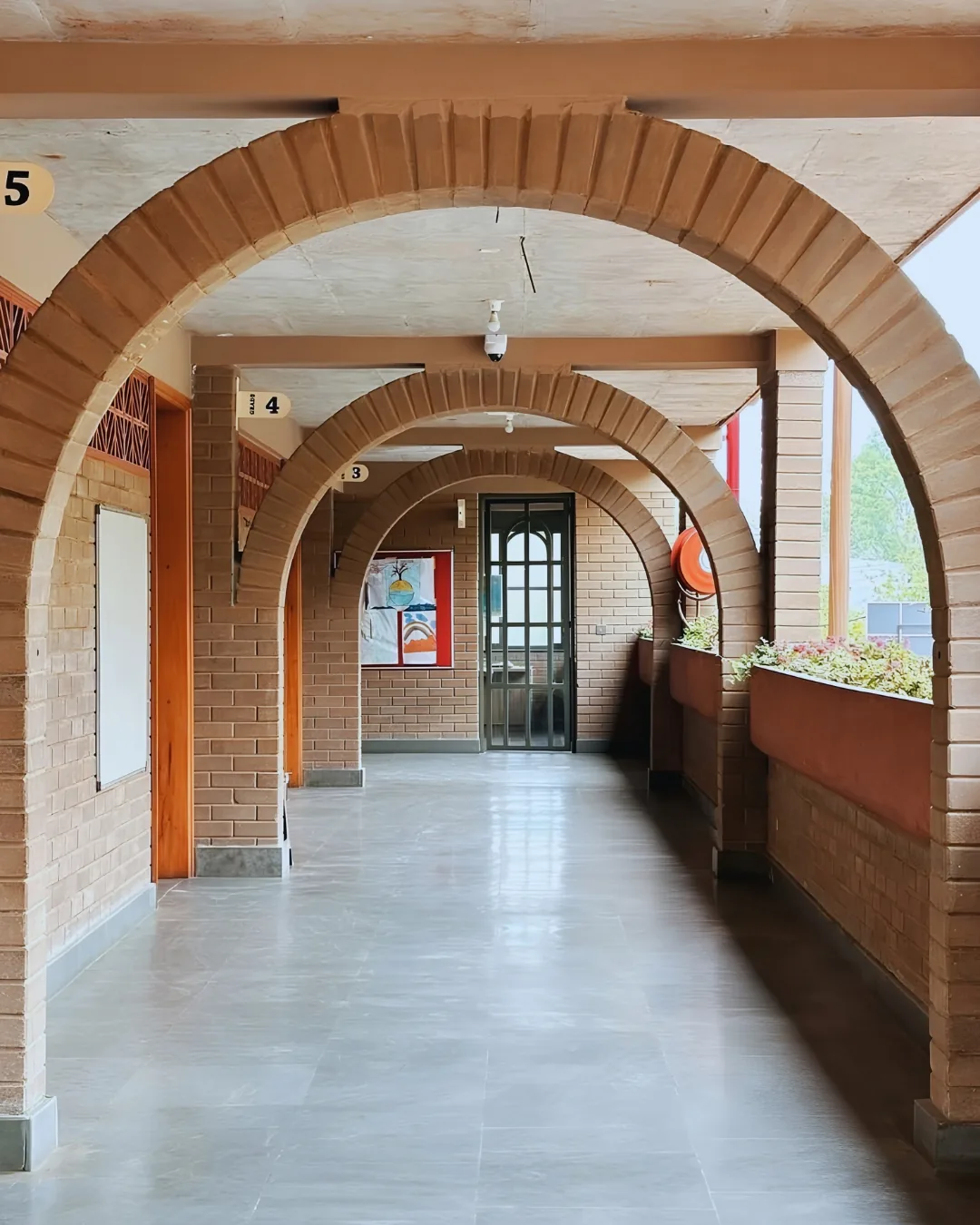 A classroom corridor running under earth-block arches, grade numbers over each door